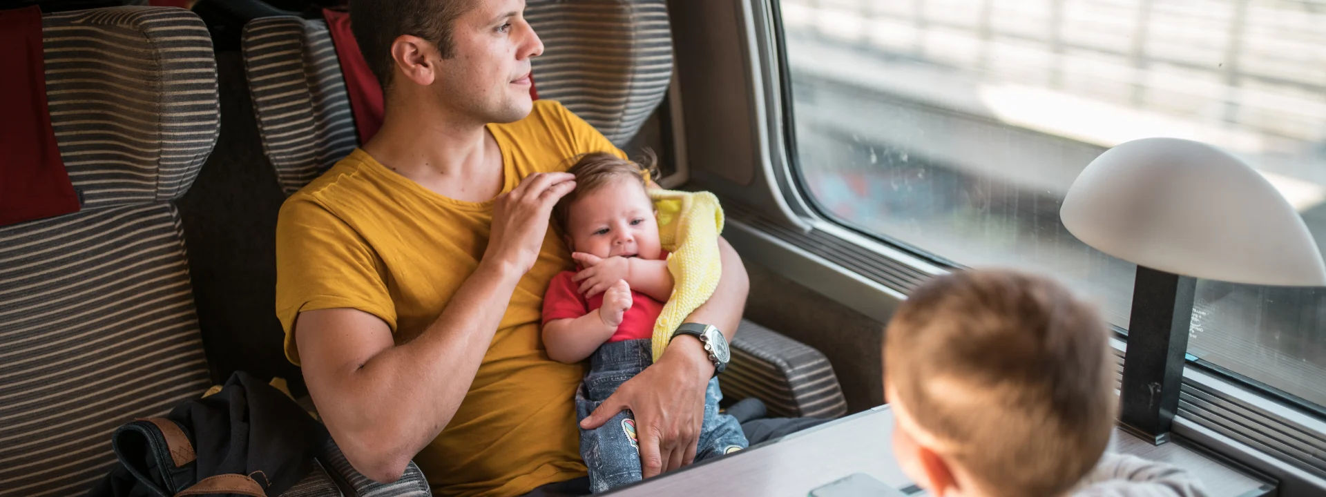 Padre con un bebé y un niño viajando en tren, seguro de viaje